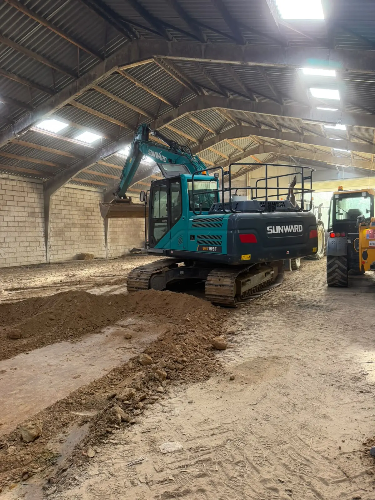 Chantier Leuze-en-Hainaut – photo 2 : pelle sur chenilles dans le bâtiment, tas de terre au premier plan